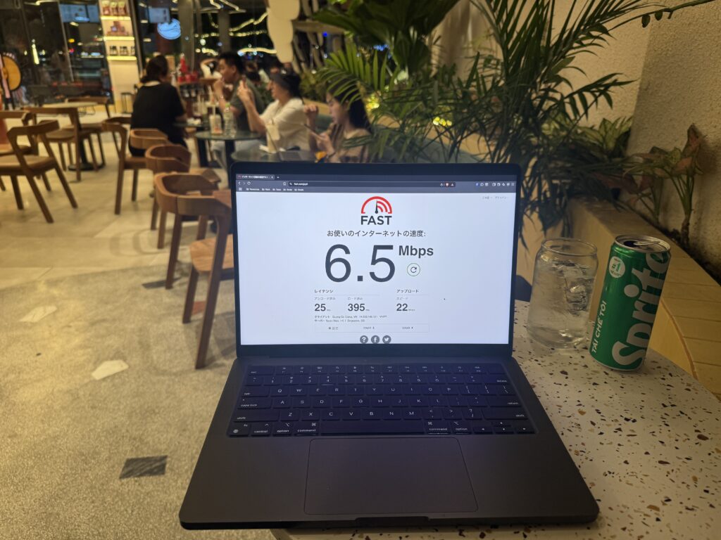 Laptop displaying 6.5Mbps download speed at Highlands Coffee with indoor seating in the background